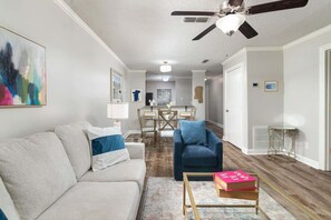A living room with a sofa, armchair, coffee table, and a ceiling fan.