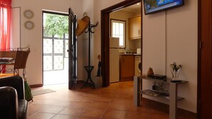 Un soggiorno con zona pranzo, una TV montata a parete e vista sulla cucina tramite una porta aperta.