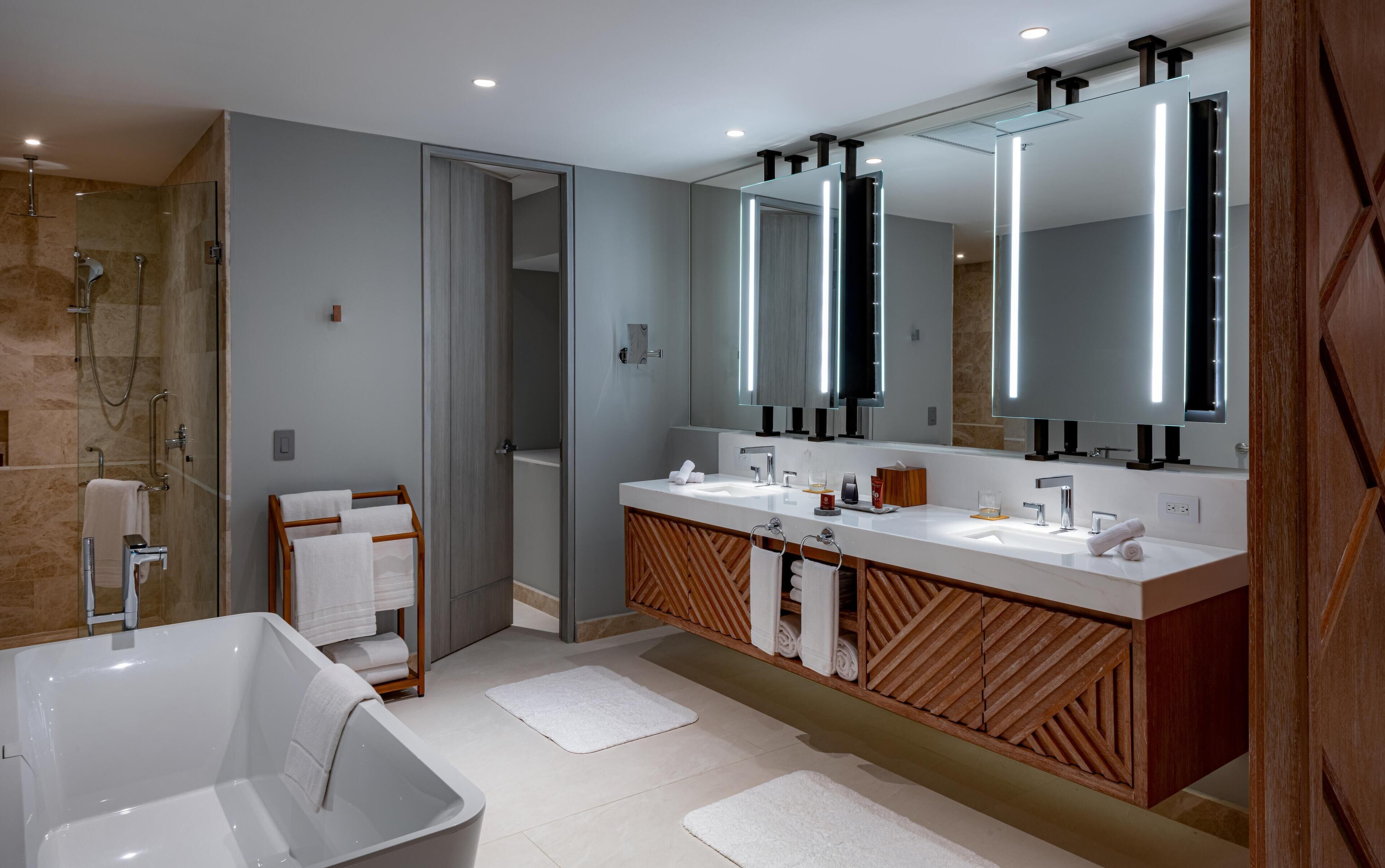 A modern bathroom with a large mirror, a bathtub, and a shower area.
