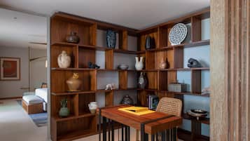 Een moderne woonkamer met een houten boekenkast vol decoratieve objecten, een eettafel met stoelen en een bank.
