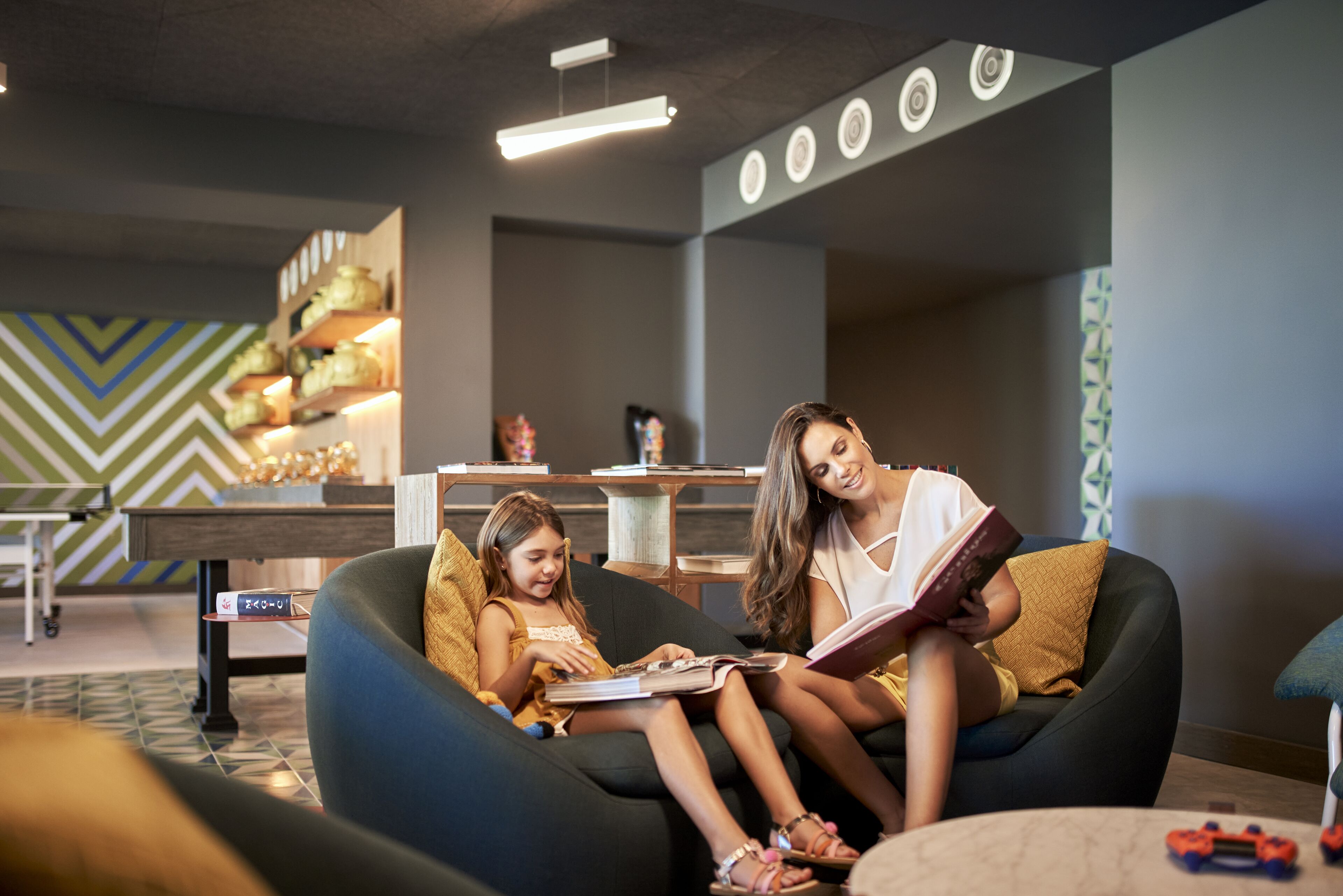 Un área de estar moderna con un sofá y sillones, una mesa de centro y una pared decorativa con azulejos estampados.