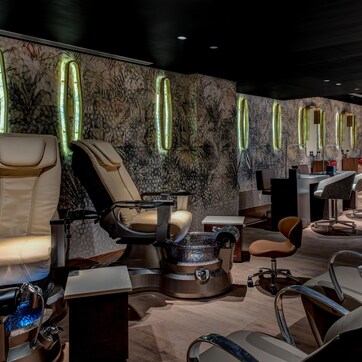 A modern spa room with massage chairs, a steam bath, and a reception desk.