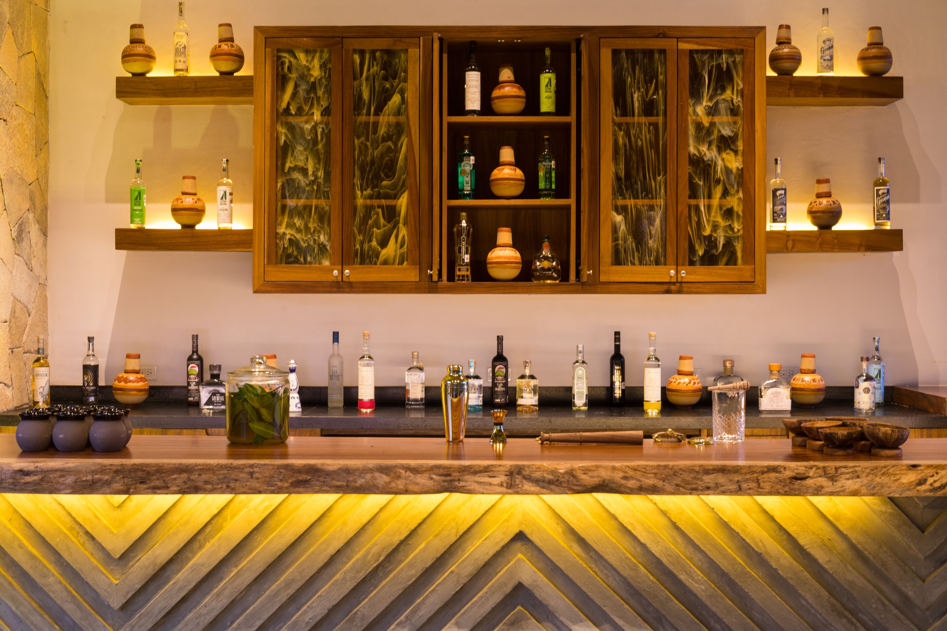A bar area with wooden shelves displaying bottles and a herringbone-patterned counter.