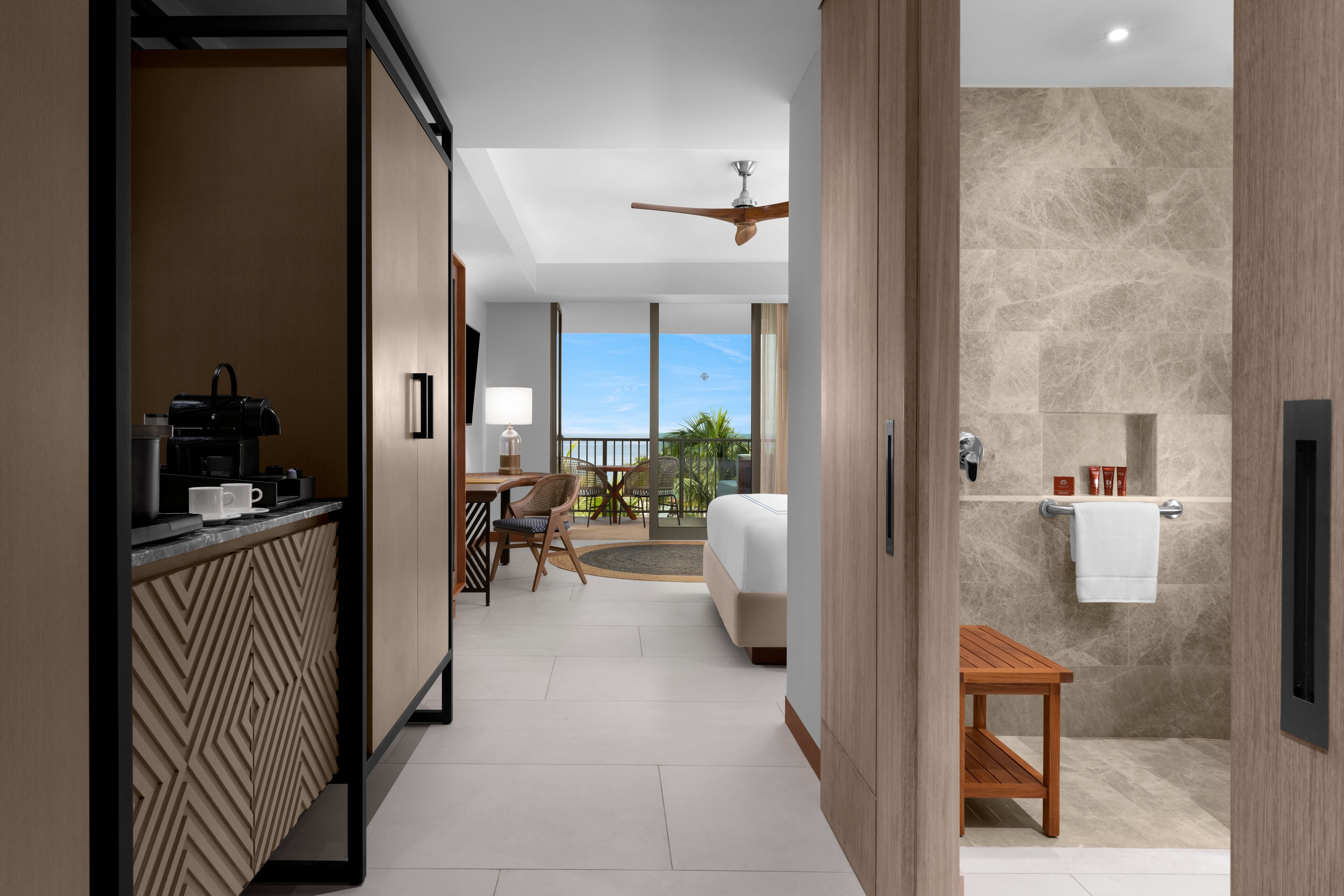 A hotel room with a kitchenette, a bed, a bathroom, and a view of the outdoors.