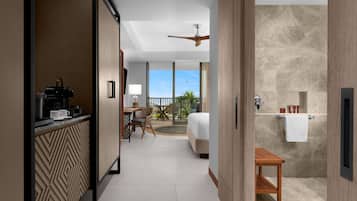 A hotel room with a kitchenette, a bed, a bathroom, and a view of the outdoors.