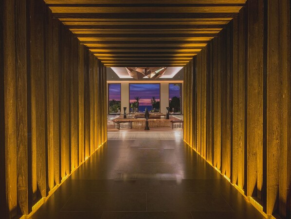 Un pasillo con paneles de madera y vistas a un atardecer a través de amplios ventanales.