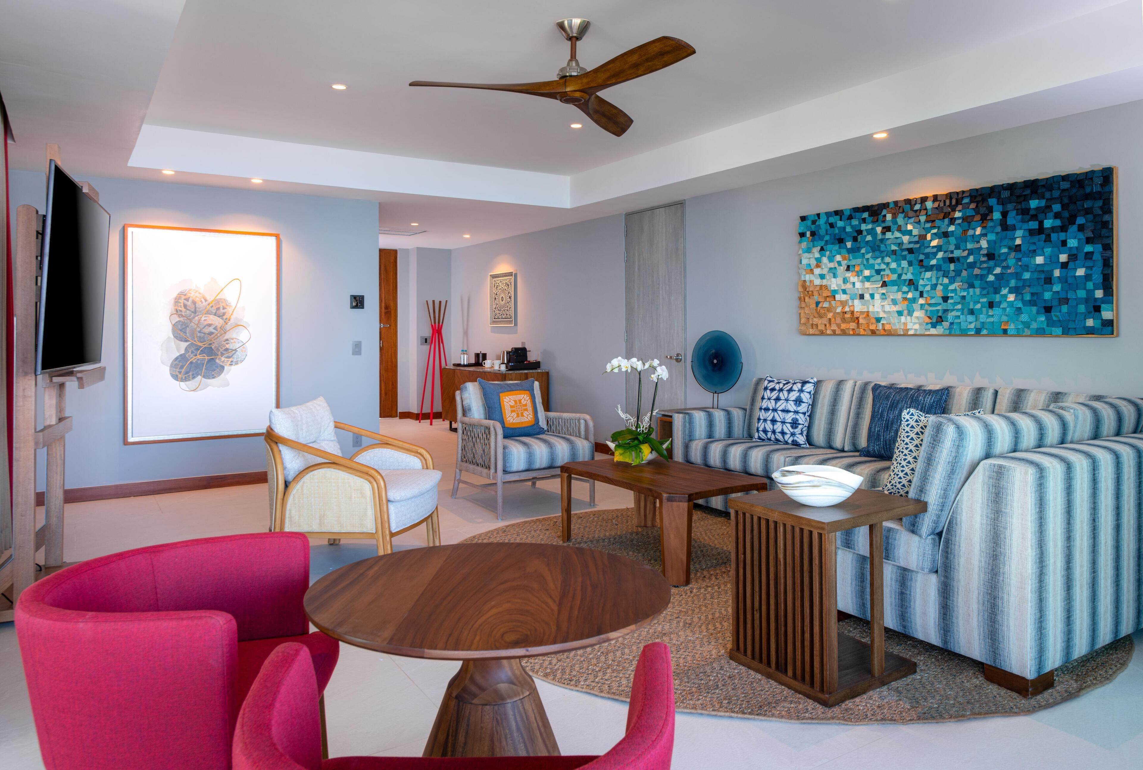 A modern living room with a sofa, chairs, a coffee table, and a ceiling fan.