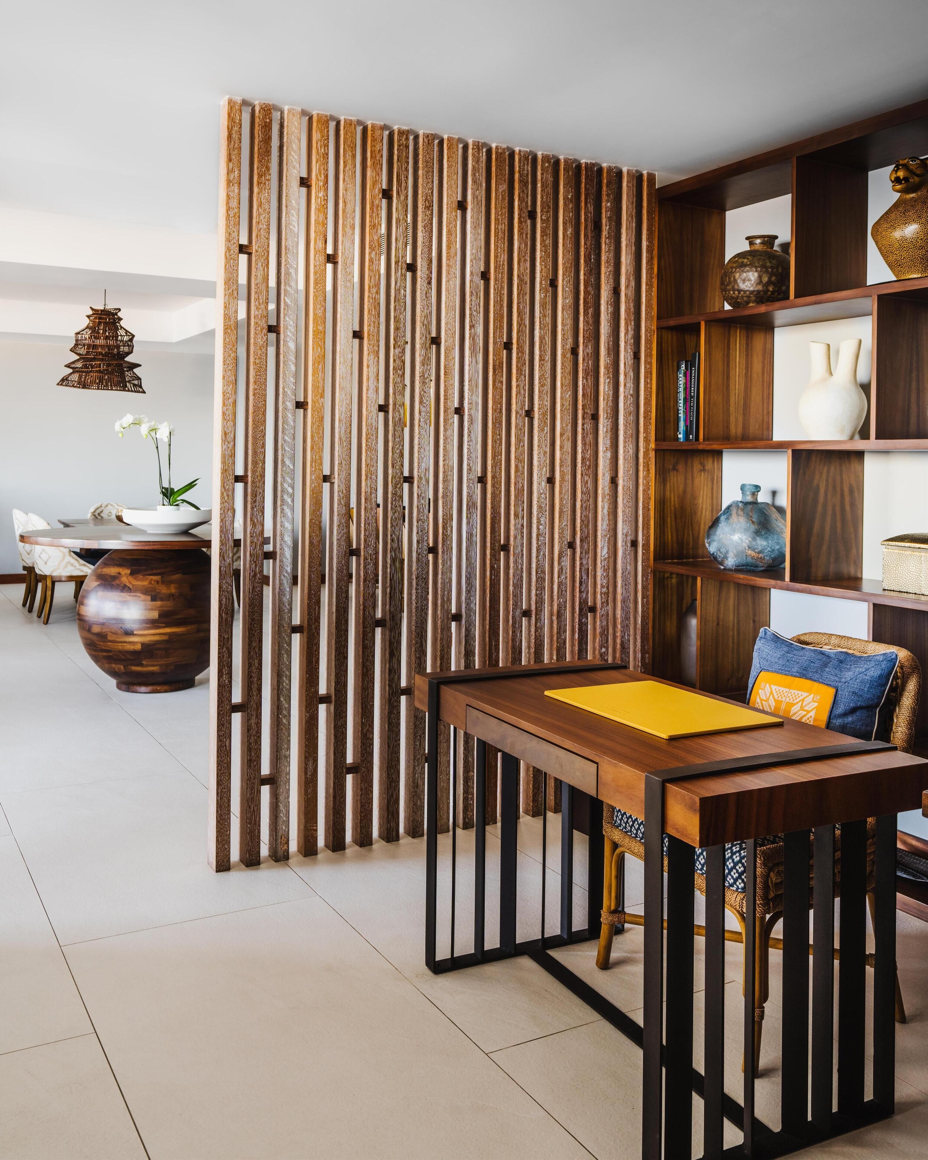 A modern living room with a wooden partition, a dining table with chairs, a bookshelf, and decorative items.