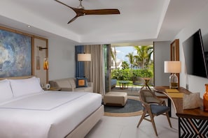 A hotel room with a large bed, a desk with a TV, a chair, and a view of the outdoors.