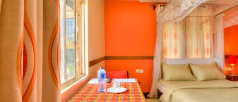 A room with a bed, a table with a water bottle, and a window with curtains.