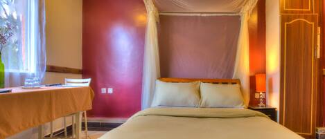 Un dormitorio ordenado con cama, mesita de noche y ventana con cortinas.