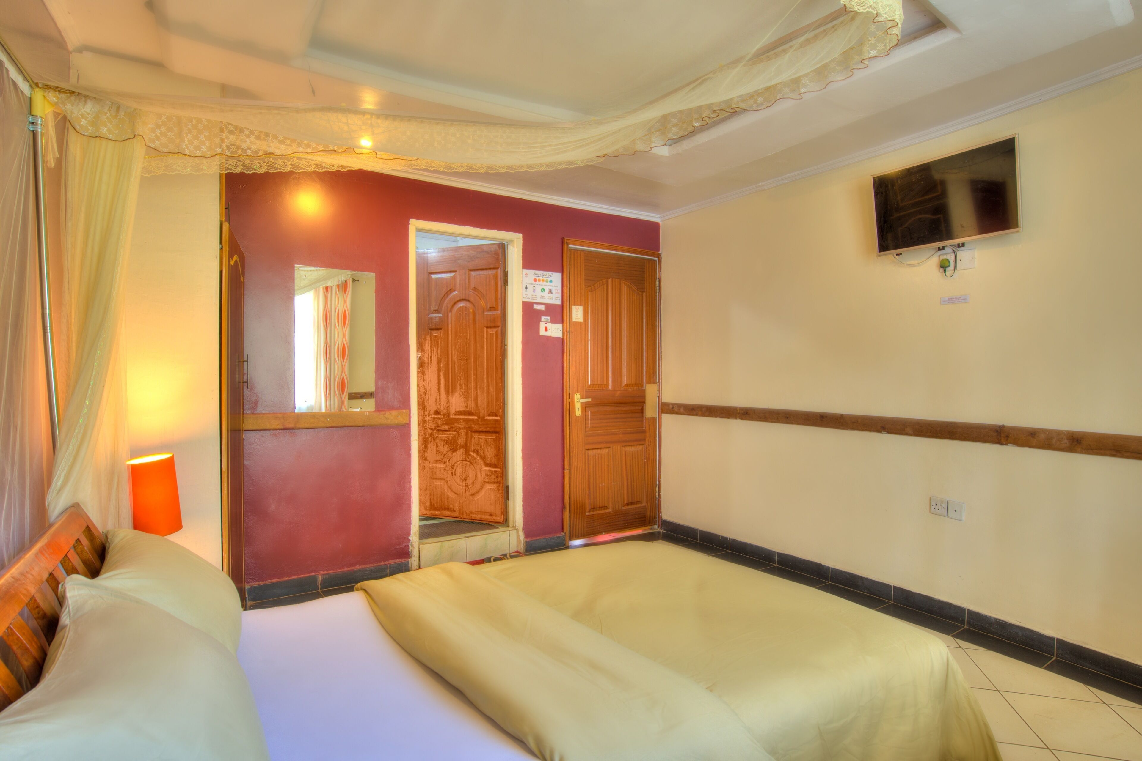 A hotel room with two beds, a television, and a mirror.