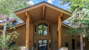 A two-story lodge with a prominent entrance, large windows, and stone pillars. - 3390 Sun Ridge Dr (Park City)