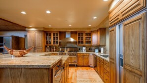 A spacious kitchen with wooden cabinets, a large island, and a built-in stove. - 3390 Sun Ridge Dr (Park City)