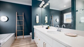 A modern bathroom with a large mirror, two sinks, a bathtub, and a wooden ladder. - 21712 Palm Ave Stay Awhile (Panama City Beach)