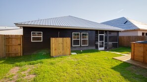 A single-story house with a dark exterior, a metal roof, and a fenced backyard. - 21712 Palm Ave Stay Awhile (Panama City Beach)