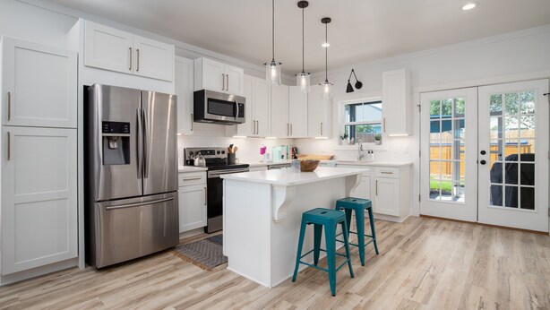 A modern kitchen with white cabinetry, stainless steel appliances, and teal bar stools.
