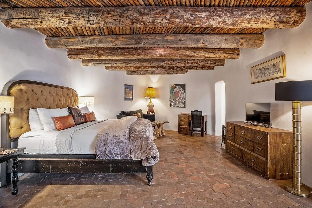Een slaapkamer met een bed, houten hoofdbord, een dressoir, een lamp en een televisie.