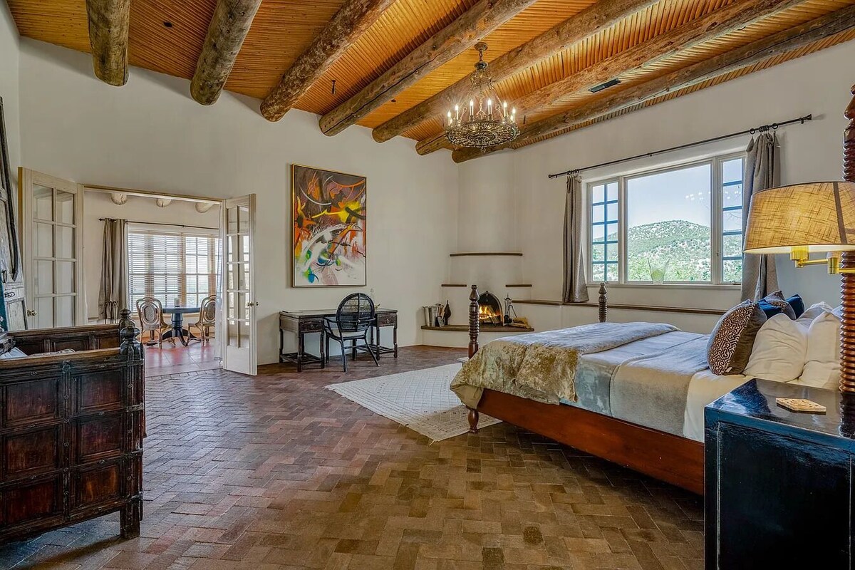 Een slaapkamer met een houten plafond, een bed, een bureau en een stoel.
