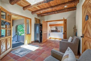 A cozy interior with a wooden ceiling, a reception desk labeled "Guest House," and a seating area with a patterned rug. - Cielo Taos (Arroyo Hondo)