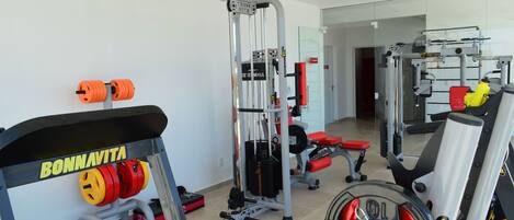 A gym with weightlifting equipment, including a bench press, squat rack, and various weights.