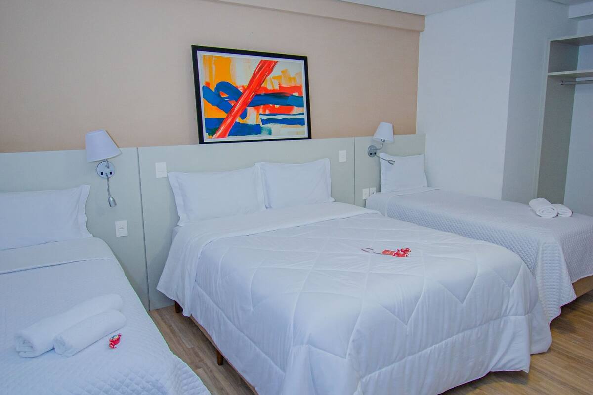 A hotel room with two beds, a painting on the wall, and a wooden floor.