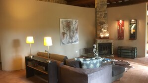 Una sala de estar acogedora con pared de piedra, chimenea, sofá y dos lámparas.