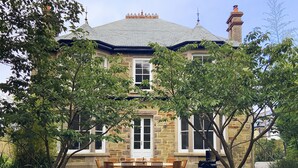 A stone house with a large front porch, a dining table, and chairs. - A substantial six double bedroom property located in the heart of St Agnes. (St Agnes)