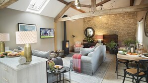 Una sala de estar acogedora con chimenea, un comedor y una encimera de cocina con frutas y flores.