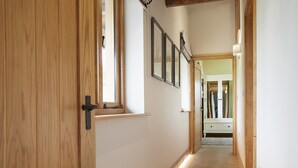 Un pasillo con puertas de madera y piso de baldosas, que conduce a una habitación con radiador y ventana.