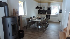 A modern kitchen with a central island, wooden flooring, and pendant lighting.