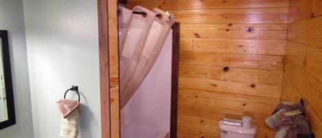 A wooden-paneled bathroom with a bathtub, toilet, and sink.