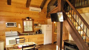 A wooden cabin interior with a kitchen, dining area, and a fireplace. - Freedom Ridge Cabins (Hill City)