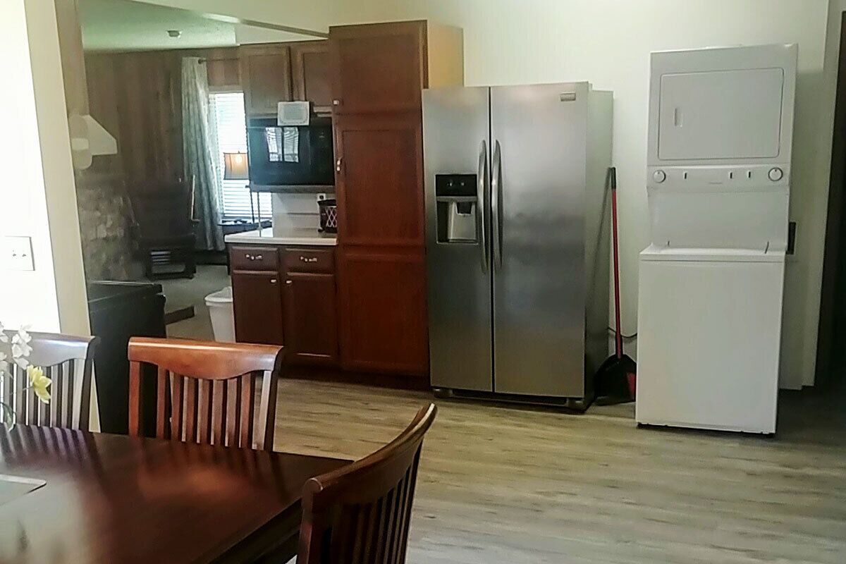A kitchen with wooden cabinets, a stainless steel refrigerator, a microwave, and a sink.