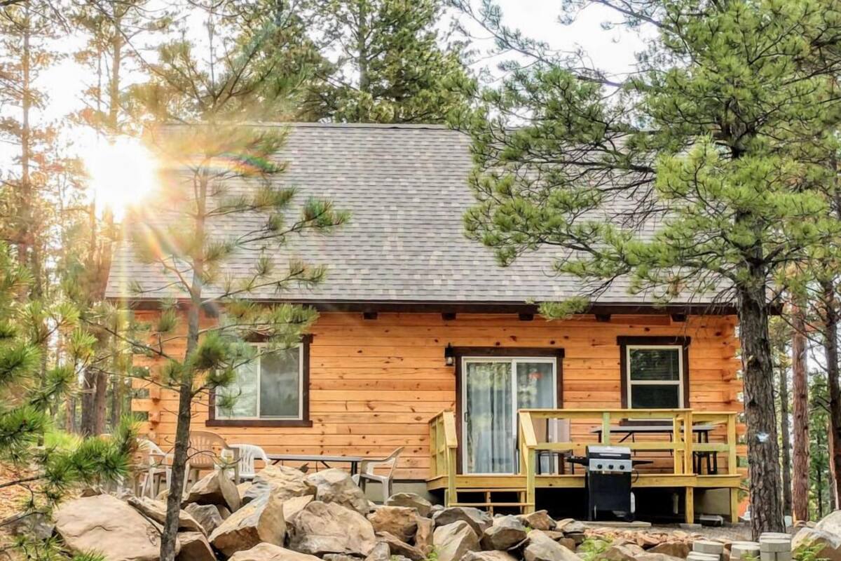 A cabin with a wooden exterior, a deck, and a grill area.