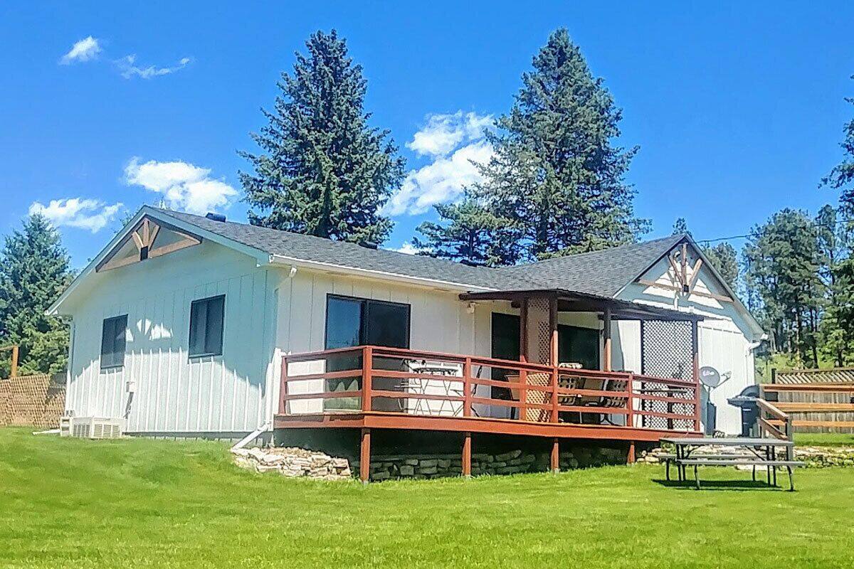 A two-story house with a covered porch and a stone foundation.