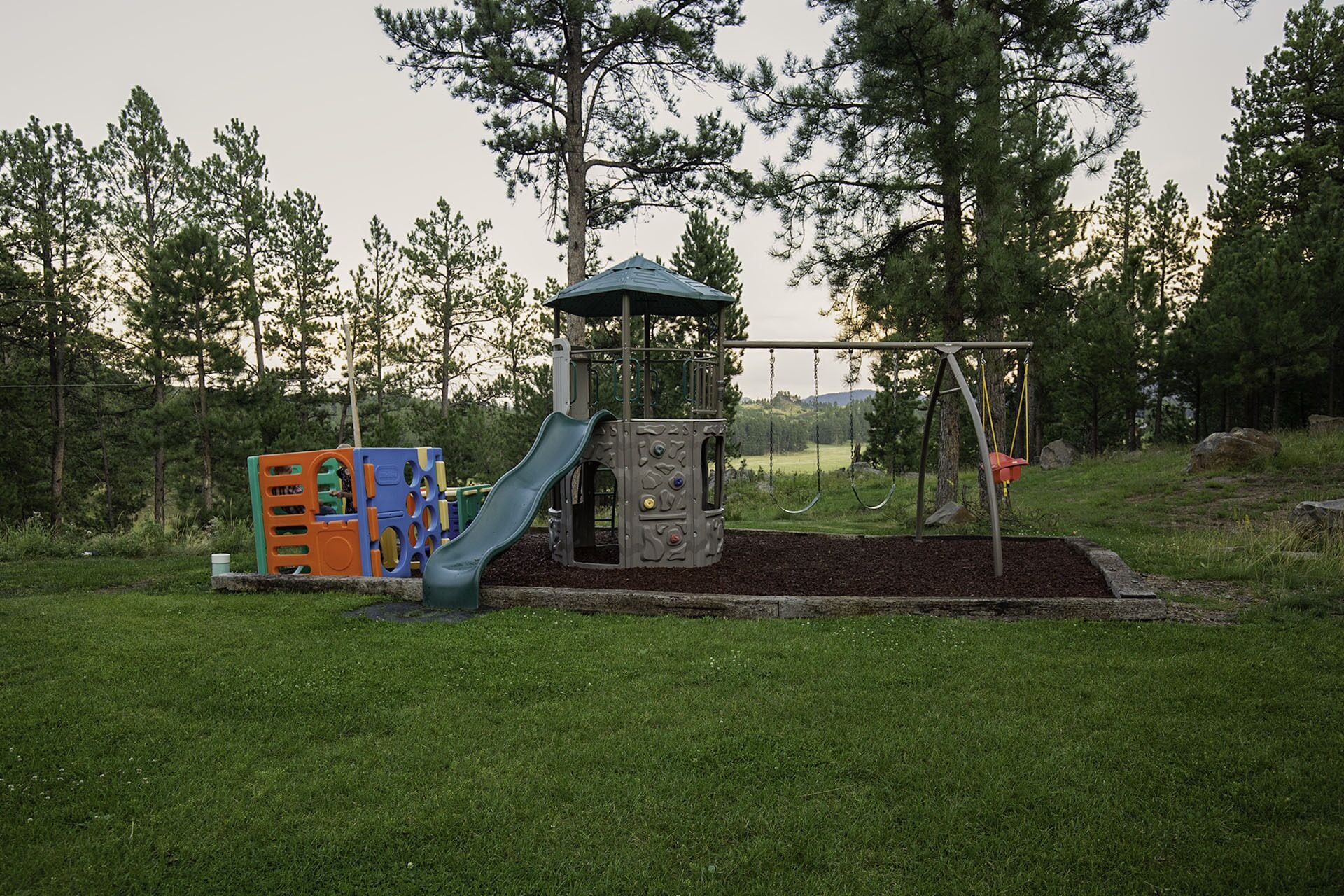 Un parque infantil con tobogán, estructura para escalar y columpios.
