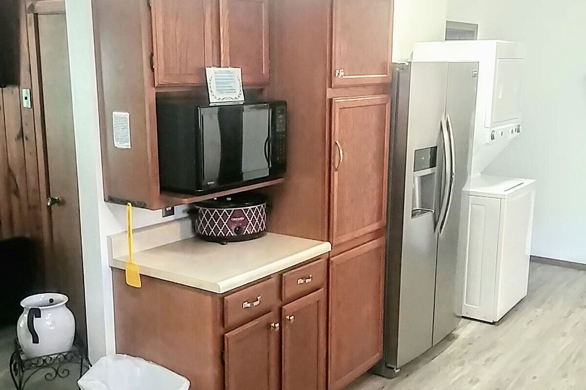 A kitchen with wooden cabinets, a microwave, a refrigerator, and a small sink.