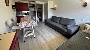 Een knus woongedeelte met een kitchenette, een eettafel, een bank en een bed.