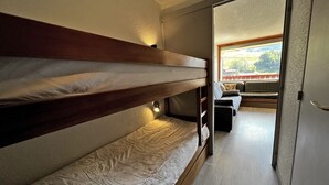 Een slaapkamer met stapelbed en uitzicht op een balkon, met een zithoek.