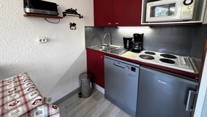 Een kleine keuken met een vaatwasser, een koffiezetapparaat en een magnetron.