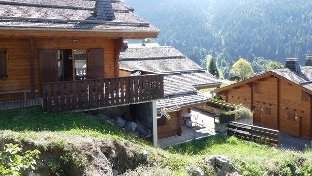 Eine Holzhütte mit Balkon mit Blick auf eine Berglandschaft.