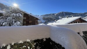 Eine verschneite Berglandschaft mit einer Holzhütte und einer Skipiste im Hintergrund.
