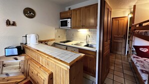 Eine kompakte Küche mit Holzausstattung, einer Mikrowelle, einem Spülbecken und einer kleinen Essecke mit einer Bank.