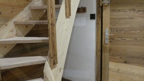 Un escalier en bois mène à une porte dotée d’une poignée en métal.