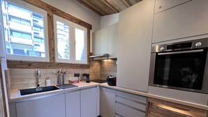 Une cuisine moderne dotée d’un four encastré, d’un évier et de meubles de rangement en bois.