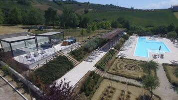 Un hôtel moderne doté d’une piscine intérieure protégée par des baies vitrées, d’un espace extérieur aménagé et offrant une vue sur la campagne environnante.