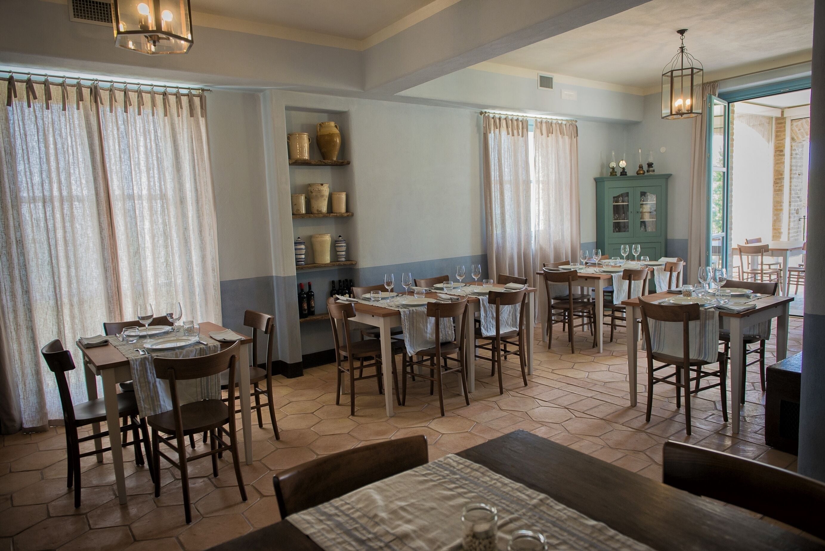 A dining area with multiple tables set for meals, wooden chairs, and a blue and white color scheme.
