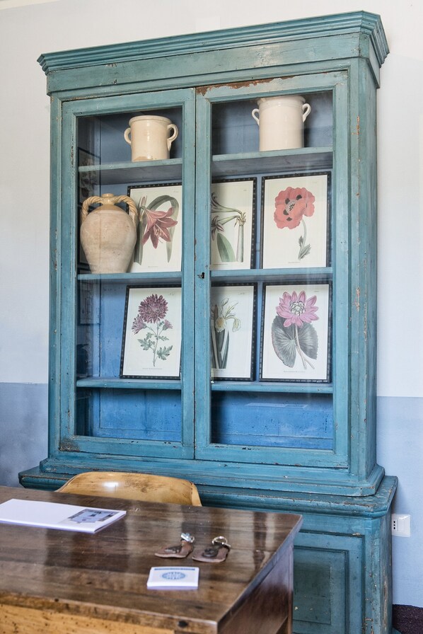 A teal cabinet with glass doors, displaying various ceramic items and framed botanical illustrations. - Villa Sant'Angelo (Alba Adriatica)