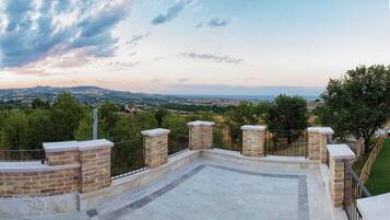 Una terraza con barandillas de piedra y vistas a un pueblo y colinas a lo lejos.